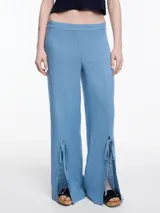 Pantalón ancho color azul, con tajos laterales en la botamanga y lazos ajustables. Confeccionado en tejido liviano de lino y viscosa.