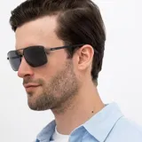 Lentes de sol INVU modelo B1007E, con montura rectangular de metal color gris plomo y lentes polarizadas color azul. Patillas azules con detalle del logo en el extremo.