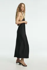 Vestido largo color rosa pálido, con escote en V pronunciado y tirantes finos tipo espagueti que se unen en la espalda. El corte es recto y holgado, con caída fluida.