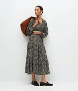 Vestido midi de viscosa con estampado de lunares multicolores sobre fondo oscuro, escote en V con cordones y mangas abullonadas.