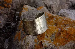 Brazalete rígido de diseño artesanal con textura irregular y acabado metálico, elaborado en bronce macizo.