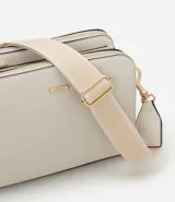 Bolso bandolera de tamaño mediano confeccionado en poliuretano color marrón, con tres compartimentos independientes con cierre de cremallera. Incluye una correa de hombro ajustable de cinta tejida bicolor y herrajes metálicos dorados.