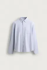 Camisa de manga larga regular fit en color marrón oscuro, confeccionada en tejido de algodón. Presenta cuello abotonado, bolsillo de parche en el pecho y cierre frontal con botones en contraste.
