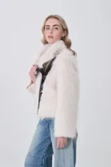 Tapado corto de piel sintética en color crema, con solapas amplias y cierre frontal asimétrico con detalles en cuero sintético oscuro.