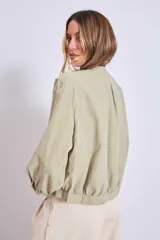 Cazadora azul de manga larga con puños elásticos, cuello redondo sin solapas y cierre frontal con botones grandes de color claro.