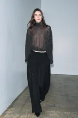 Blusa negra con estampado de lunares blancos, cuello redondo con lazadas y manga larga con puños ajustados. El bajo es ajustable con cordones.