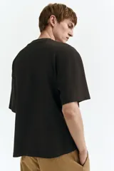Remera negra de punto de algodón pesado, con cuello redondo ribeteado acanalado, hombros caídos y mangas cortas de corte holgado.