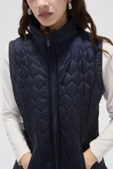 Chaleco acolchado negro con diseño de costuras geométricas, cierre frontal completo y bolsillos laterales.