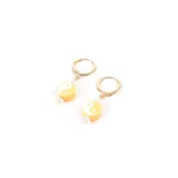 Aros colgantes dorados con dije circular naranja con símbolo de yin yang blanco y cuentas de perlas sintéticas.