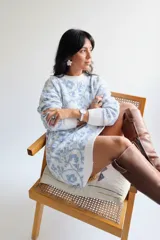 Suéter largo de punto con diseño floral en tonos blanco y azul, de corte holgado, cuello redondo y mangas largas con puños acanalados. Puede utilizarse como vestido tejido.