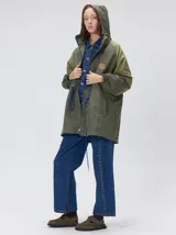 Campera tipo piloto con capucha, cierre frontal con botones y detalle de costuras en zigzag. Presenta cordones ajustables en la cintura y capucha, puños elásticos y logo bordado en el pecho.