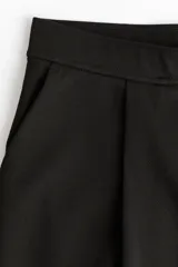 Pantalón de punto de corte holgado y tiro alto con elástico oculto en la cintura, piernas amplias con pinzas y bolsillos al bies.