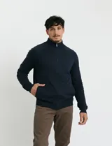 Cardigan de punto color azul marino con cuello alto, cierre frontal completo y mangas ranglan. Presenta bolsillos laterales de ribete y puños y ruedo acanalados.