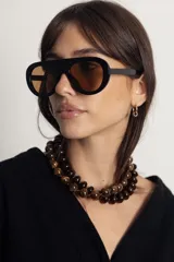Lentes de sol con armazón de policarbonato negro y diseño de puente alto, con cristales en tono marrón.