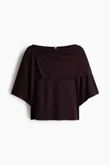 Top corto color bordó en punto elástico de viscosa, con escote bote, hombros caídos, mangas cortas amplias y sección superior superpuesta con diseño asimétrico efecto capa.