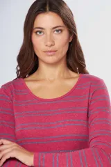 Remera de manga larga con cuello redondo, confeccionada en tejido rayado horizontal en tonos rojo y azul, con detalle de pin metálico con logo en la parte frontal.