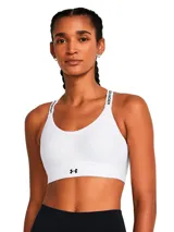 Top deportivo Under Armour de sujeción media, color blanco, con tirantes ajustables que incluyen el logo de la marca y banda elástica inferior con logo central. Cuenta con paneles laterales de malla para ventilación y relleno moldeado.