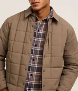 Campera capitoneada Blue Steel de color marrón, con cuello polo, manga larga, puños ajustados, cierre frontal con botones a presión y un bolsillo vertical en el pecho.