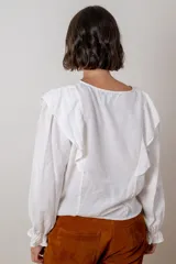 Blusa de algodón color bordó, con diseño de volados en los hombros, mangas largas con puños elásticos y corte holgado.