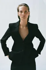 Blazer entallada de Zara Woman Collection color negro, con cuello solapa de muescas, manga larga y cierre frontal de dos botones. Cuenta con bolsillos de vivo en el delantero, pespuntes a tono y forro interior.