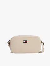 Cartera tipo bandolera Tommy Jeans de diseño compacto y acabado liso en color beige. Cuenta con cierre de cremallera superior y una insignia metálica distintiva de la marca en la parte frontal.