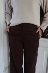 Pantalón de corte sastre con pierna recta, color marrón chocolate, con detalle de rayas laterales en contraste.