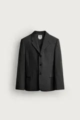 Blazer de corte regular fit color gris oscuro, confeccionado en tejido con lana. Cuenta con cuello con solapas de muesca, cierre frontal con tres botones, bolsillos con solapa en la cadera y un bolsillo de vivo en el pecho.