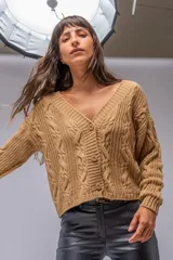 Saco tejido de punto color camel, con diseño de trenzas verticales, escote en V y cierre frontal con botones al tono. Presenta mangas largas con puños acanalados y un corte a la cintura.
