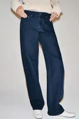 Jeans de tiro medio con diseño de perneras curvas y corte recto, confeccionados en denim con estampado paisley en tonos marrones y beige. Presentan diseño clásico de cinco bolsillos, trabillas para cinturón y cierre frontal con cremallera y botón metálico.