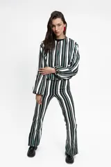 Pantalón de corte semi oxford con estampado de rayas verticales en tonos blanco, negro y verde. Presenta aberturas en el ruedo y está confeccionado en tela crepe.