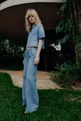 Camisa de denim de corte recto y manga corta, con cuello solapa, cierre frontal con cremallera y dos bolsillos delanteros de plastrón.