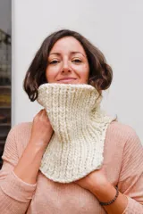 Cuello tejido a mano en lana merino color crudo, con textura acanalada y aberturas laterales.