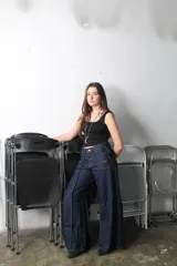 Pantalón jean azul oscuro de corte wide leg, con diseño holgado, bolsillos delanteros aplicados con detalles bordados y costuras verticales destacadas a lo largo de las piernas.