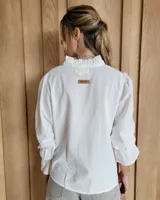 Blusa de algodón color azul, de corte suelto, con mangas largas abullonadas y cuello con volados y escote en V.