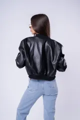 Campera estilo bomber de cuero sintético en color negro, con cierre frontal, cuello, puños y ruedo acanalados. Presenta un diseño corto y holgado.