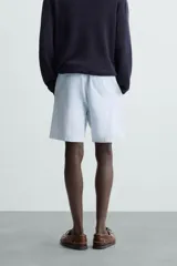 Bermuda azul marino de corte regular fit, confeccionada en tejido de algodón y lino. Cuenta con bolsillos frontales y traseros, cierre frontal con cremallera y botón.