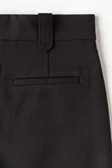 Short negro de tiro alto con pliegues tableados, bolsillos al bies y corte holgado.