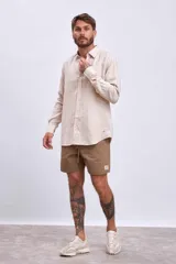 Camisa beige de lino, de corte clásico, manga larga y cuello abotonado.