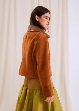 Chaqueta de gamuza color óxido, con cuello clásico en tono marrón más oscuro y cierre frontal metálico.