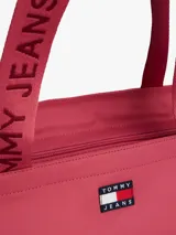 Cartera tipo tote de Tommy Jeans, confeccionada en poliéster con acabado liso. Presenta un compartimento principal con cierre de cremallera, asas superiores con la inscripción de la marca y el parche distintivo de Tommy en el frente.