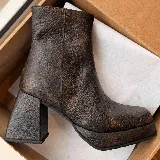 Bota corta de cuero vacuno con textura efecto cocodrilo, color negro. Presenta punta cuadrada, plataforma y taco cuadrado forrado en el mismo material. Incluye cierre lateral interno.