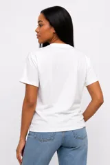 Remera de manga corta color beige, con cuello redondo y diseño de estampado floral grande en el frente.