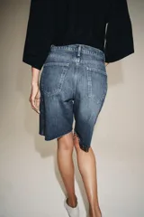 Bermuda de denim color bordó, de tiro medio y corte relaxed, con diseño de cinco bolsillos, trabillas para cinto y bajo desflecado.