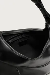 Bolso de hombro asimétrico color negro con acabado liso. Cuenta con un compartimento principal con cierre de cremallera y un bolsillo frontal con cremallera. Incluye asa de hombro ajustable.