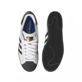 Zapatillas Adidas Superstar ADV color blanco hueso con puntera de goma negra, tres tiras laterales negras y contrafuerte trasero negro.