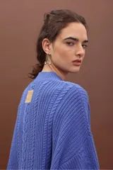 Sweater de punto negro con diseño de trenzas verticales, cuello alto y corte holgado de estilo oversize.