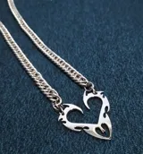Collar de dos cadenas plateadas con un dije central que forma un corazón con diseño tribal o de llamas, con recortes internos.