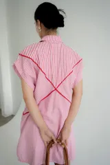 Vestido camisero corto blanco de algodón con bordados negros, cuello camisero, cierre frontal con botones y sin mangas.