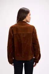 Campera de terciopelo color marrón chocolate, con cierre frontal, bolsillos laterales y elástico en el ruedo. Presenta un diseño de corte holgado con costuras marcadas.