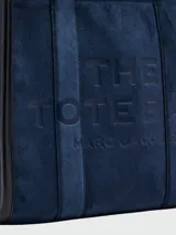 Bolso tote mediano Marc Jacobs The Suede Leather Blocked, color azul marino, confeccionado en gamuza con detalles y asas en cuero liso negro. Presenta un compartimento principal con cierre superior y correa ajustable y desmontable para llevar al hombro o cruzado.
